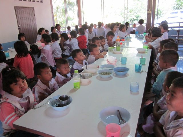 Children eating at a long table in a school canteen