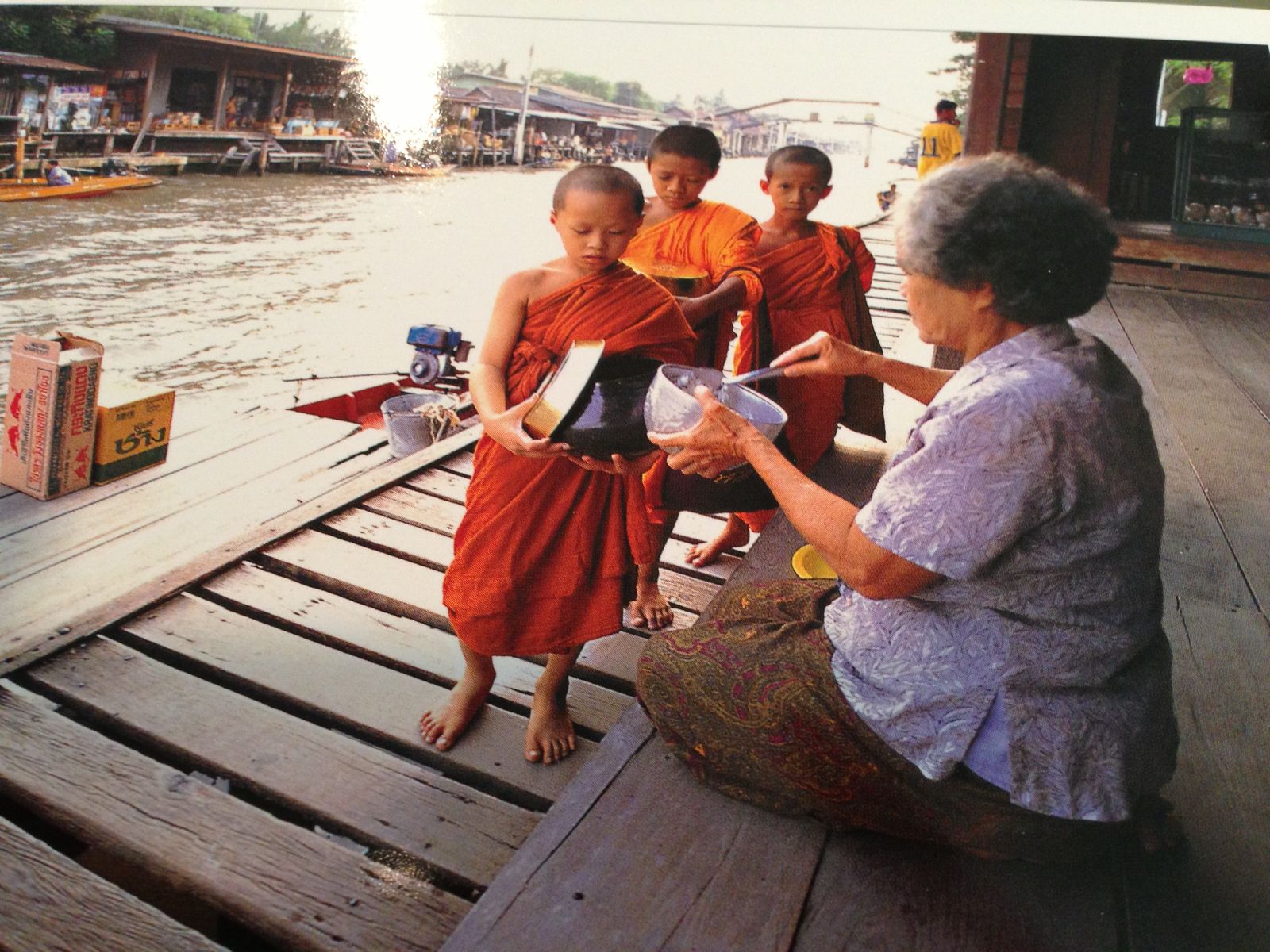 A woman handing goods across boats at a river market