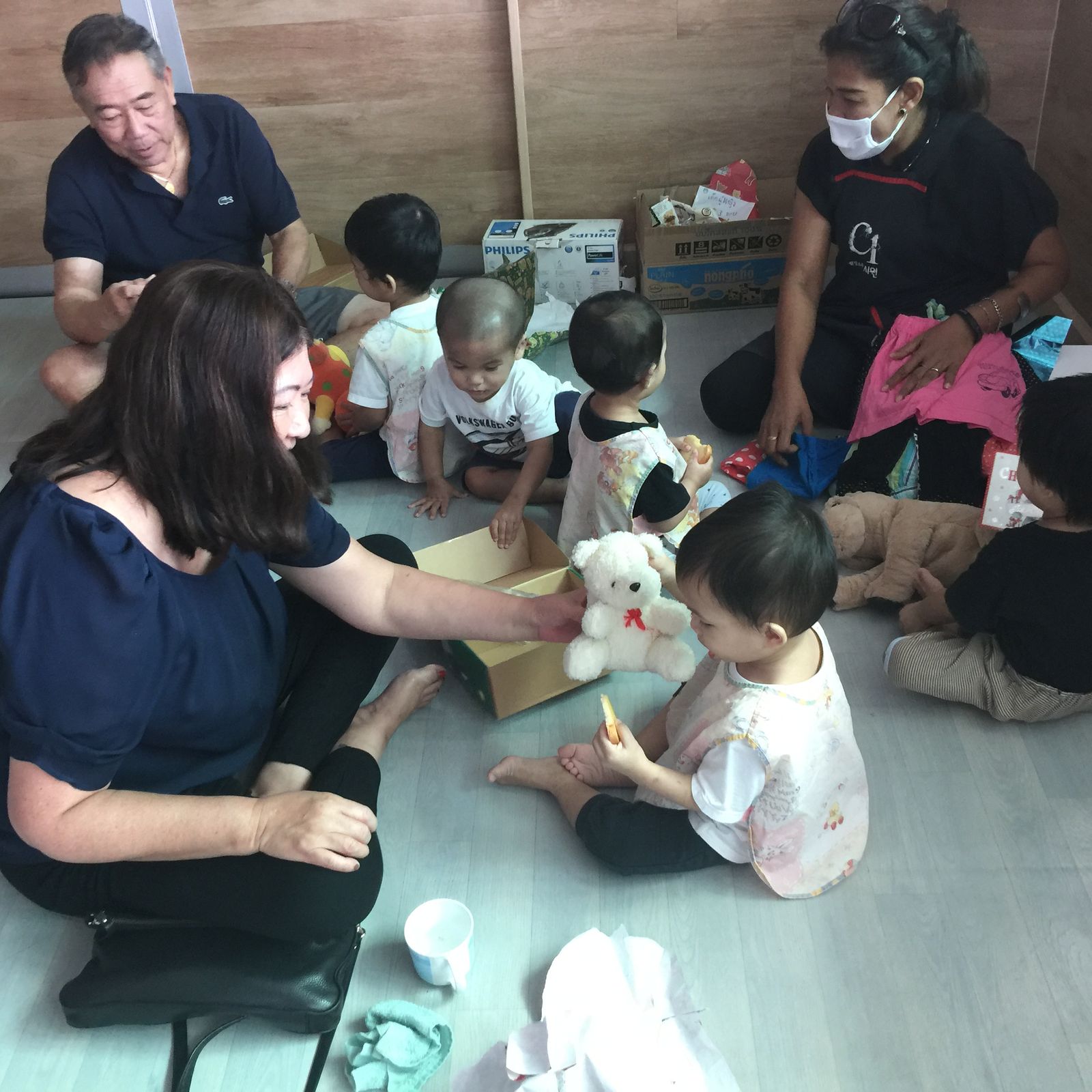 Vida sitting on the floor playing with toddlers at an orphanage